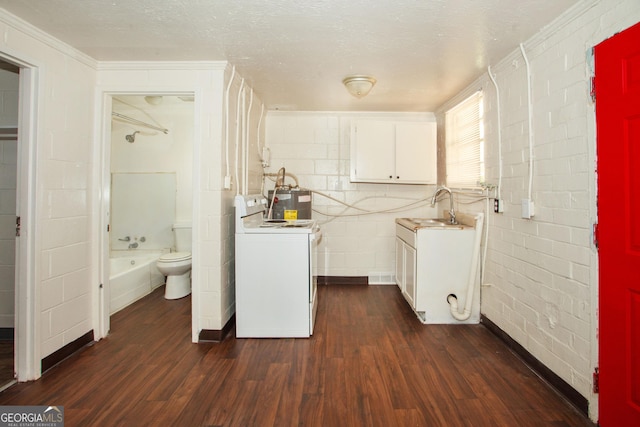 clothes washing area with sink, dark hardwood / wood-style floors, crown molding, a textured ceiling, and washer / dryer