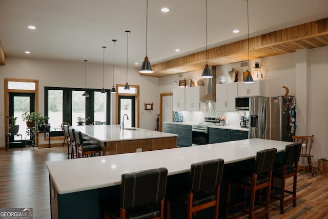 kitchen featuring a kitchen bar, a large island with sink, pendant lighting, and appliances with stainless steel finishes