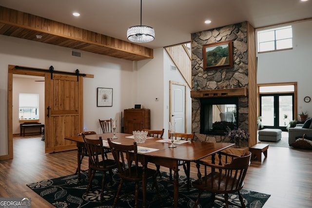 dining area featuring a barn door, wood-type flooring, french doors, and a chandelier