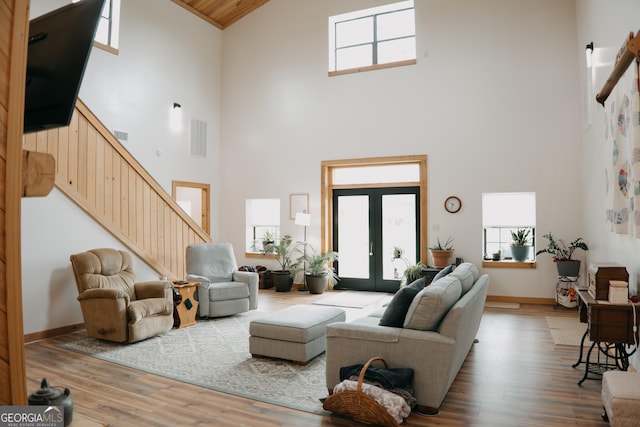 living room featuring a wealth of natural light, french doors, high vaulted ceiling, and hardwood / wood-style flooring