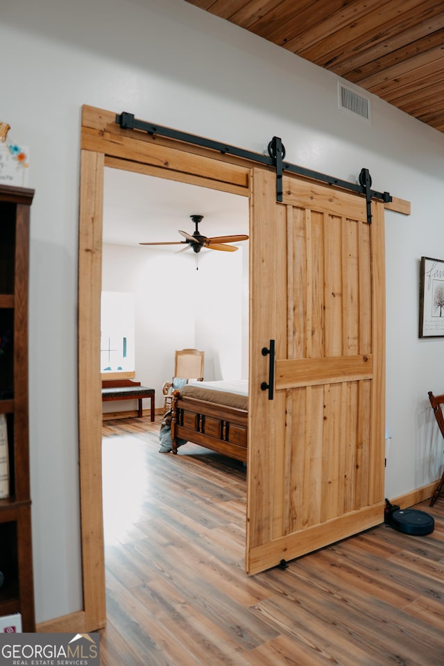 interior space featuring hardwood / wood-style flooring, a barn door, and wooden ceiling