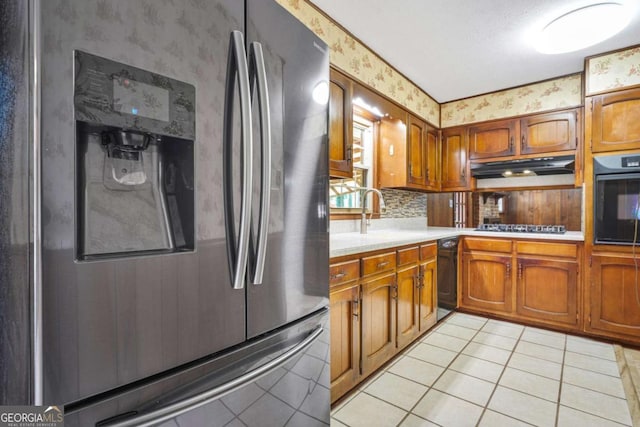 kitchen with black appliances, backsplash, light tile patterned floors, and sink