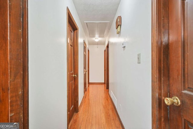 corridor featuring light hardwood / wood-style floors and a textured ceiling