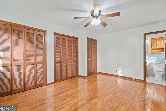 unfurnished bedroom with ensuite bathroom, ceiling fan, multiple closets, and light hardwood / wood-style floors