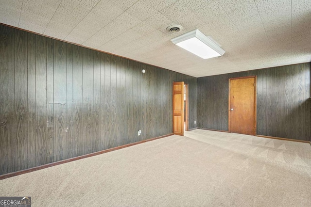 unfurnished room with carpet and wood walls