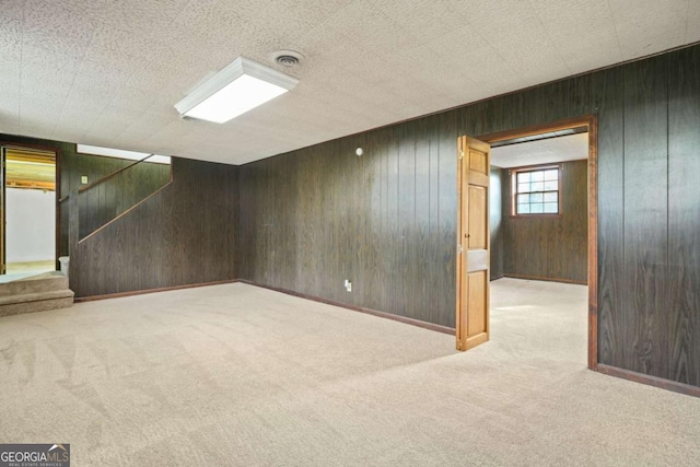 basement featuring light carpet and wooden walls