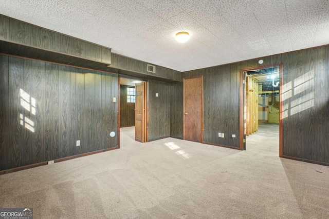 carpeted spare room with wooden walls