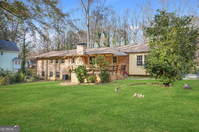 back of property with a wooden deck, a yard, and central AC