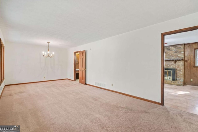 carpeted empty room featuring heating unit and an inviting chandelier