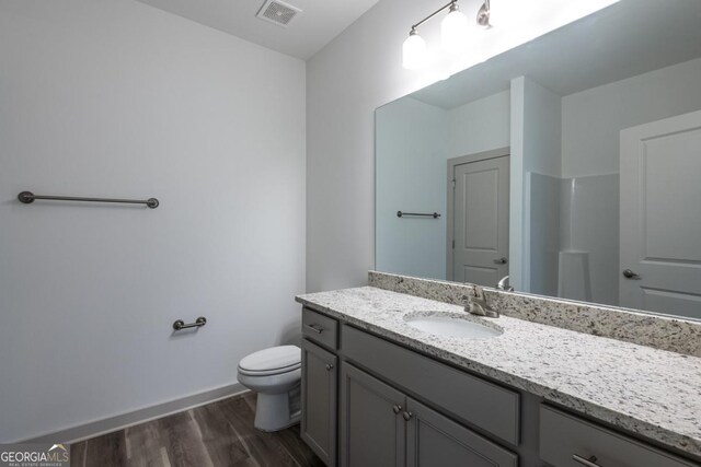 bathroom featuring walk in shower, hardwood / wood-style floors, vanity, and toilet