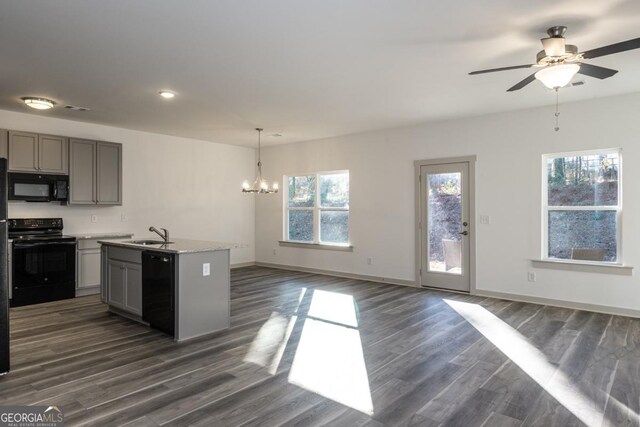 kitchen with a kitchen island with sink, dark hardwood / wood-style flooring, black appliances, and ceiling fan with notable chandelier