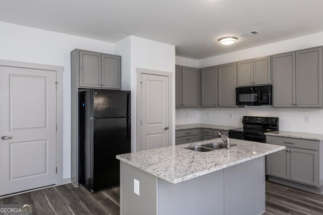 kitchen with dark hardwood / wood-style flooring, sink, an island with sink, and black appliances