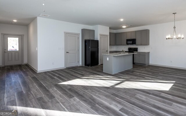 kitchen featuring gray cabinets, dark hardwood / wood-style flooring, an island with sink, and black appliances