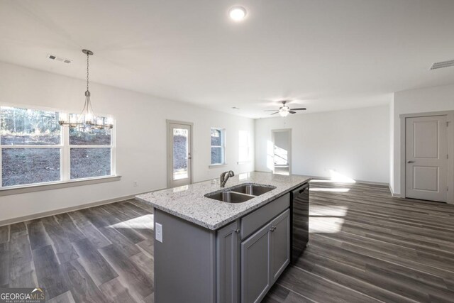 kitchen with ceiling fan with notable chandelier, dark wood-type flooring, sink, decorative light fixtures, and an island with sink