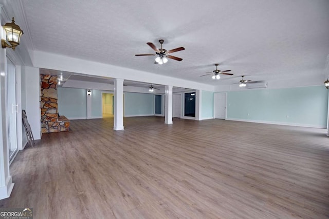 unfurnished living room featuring a wall unit AC, wood-type flooring, and a textured ceiling