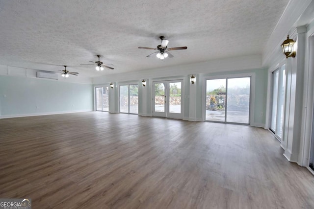 unfurnished living room featuring hardwood / wood-style floors, a textured ceiling, a wall mounted AC, and ceiling fan