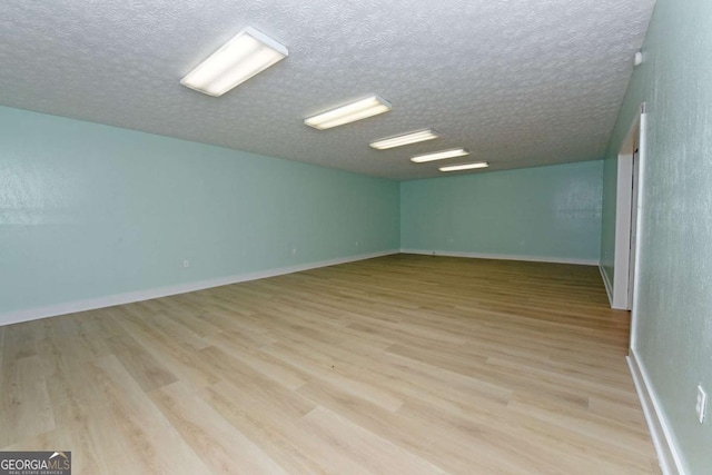 empty room with light wood-type flooring and a textured ceiling