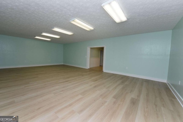 empty room featuring light wood-type flooring and a textured ceiling