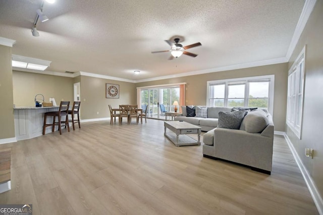 living room with a textured ceiling, light wood-type flooring, ceiling fan, and ornamental molding