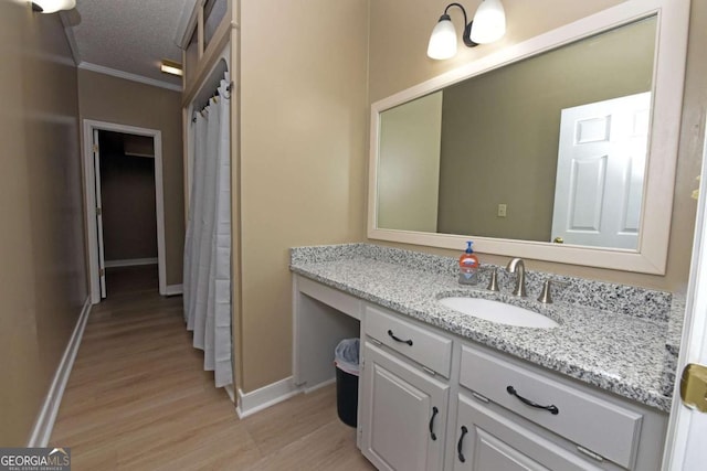 bathroom with hardwood / wood-style floors, vanity, a textured ceiling, and ornamental molding
