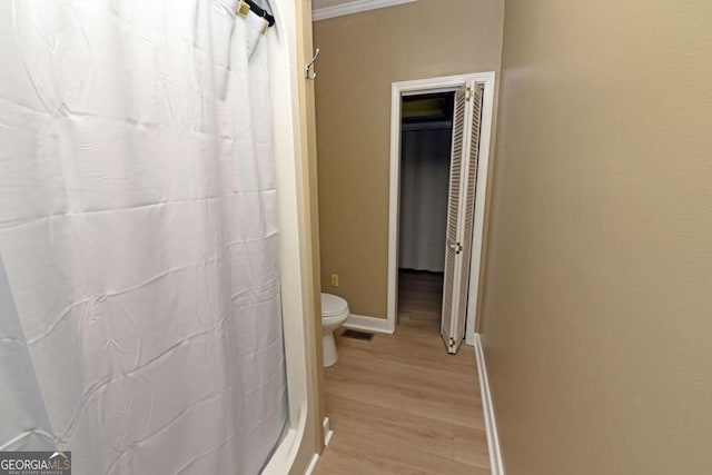 bathroom featuring walk in shower, toilet, ornamental molding, and hardwood / wood-style flooring