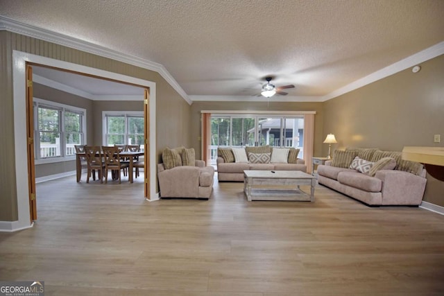 living room featuring ceiling fan, light hardwood / wood-style floors, a textured ceiling, and ornamental molding