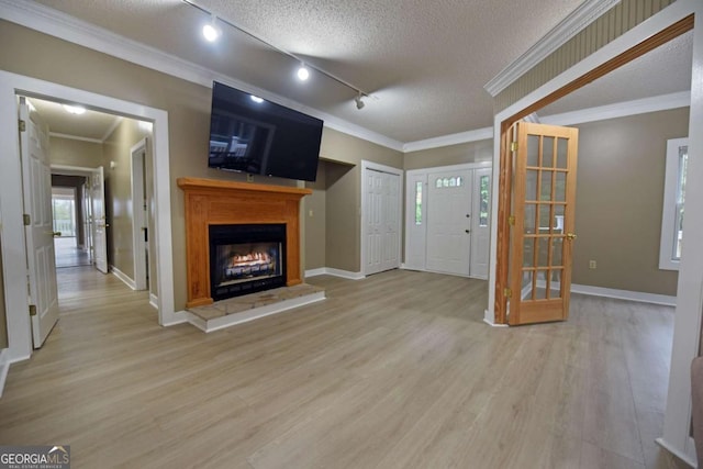 unfurnished living room with rail lighting, light hardwood / wood-style floors, ornamental molding, and a textured ceiling
