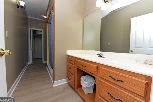 bathroom with hardwood / wood-style floors, vanity, a textured ceiling, and ornamental molding