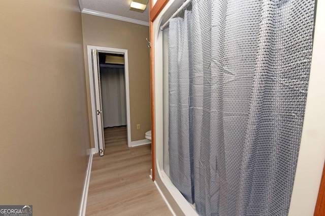 interior space with a shower with curtain, crown molding, toilet, a textured ceiling, and wood-type flooring