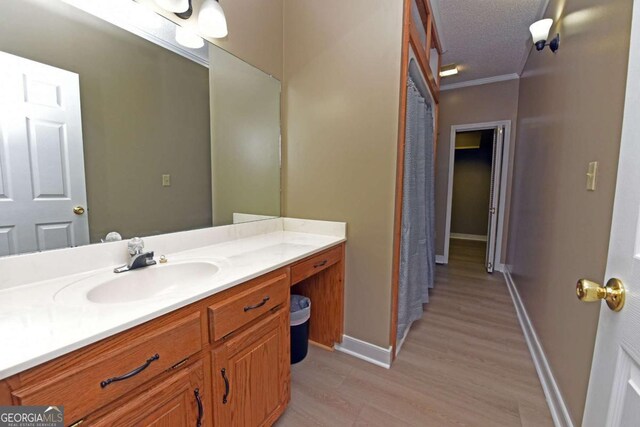 bathroom with vanity, ornamental molding, a textured ceiling, and hardwood / wood-style flooring