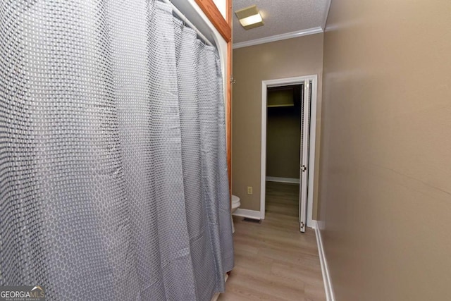 interior space featuring hardwood / wood-style floors, toilet, crown molding, and a textured ceiling