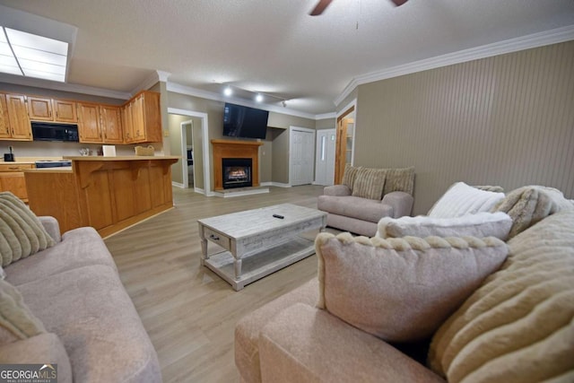 living room with a textured ceiling, light hardwood / wood-style flooring, ceiling fan, and ornamental molding