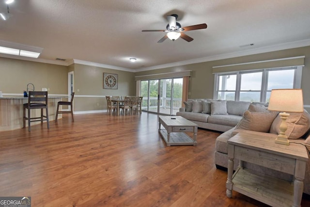 living room with crown molding, ceiling fan, a textured ceiling, and hardwood / wood-style flooring