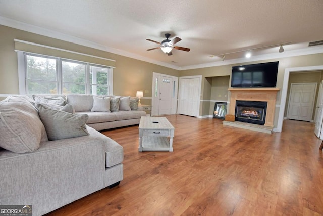 living room with track lighting, ornamental molding, a textured ceiling, ceiling fan, and hardwood / wood-style flooring