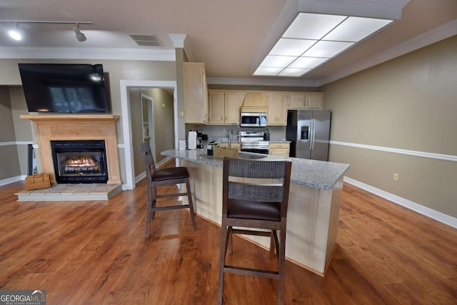 kitchen with dark hardwood / wood-style flooring, a kitchen bar, crown molding, and appliances with stainless steel finishes