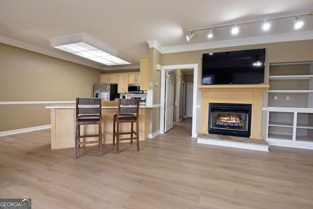 kitchen featuring kitchen peninsula, appliances with stainless steel finishes, track lighting, and a breakfast bar area