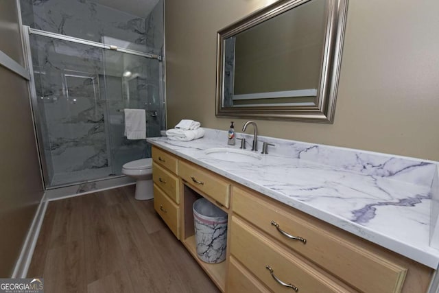 bathroom with hardwood / wood-style floors, vanity, toilet, and a shower with door