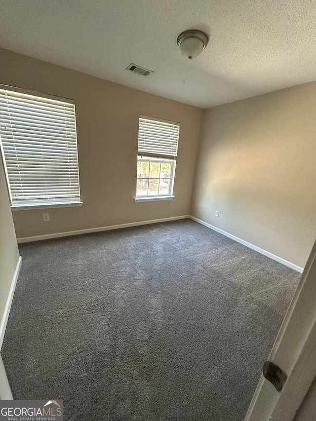 carpeted empty room featuring a textured ceiling