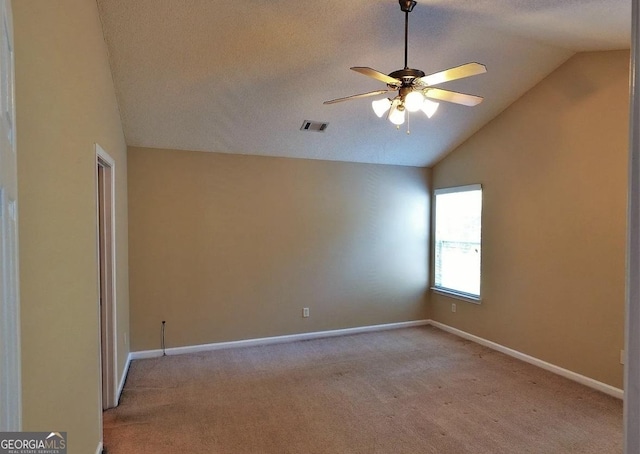 carpeted empty room featuring a textured ceiling, ceiling fan, and lofted ceiling