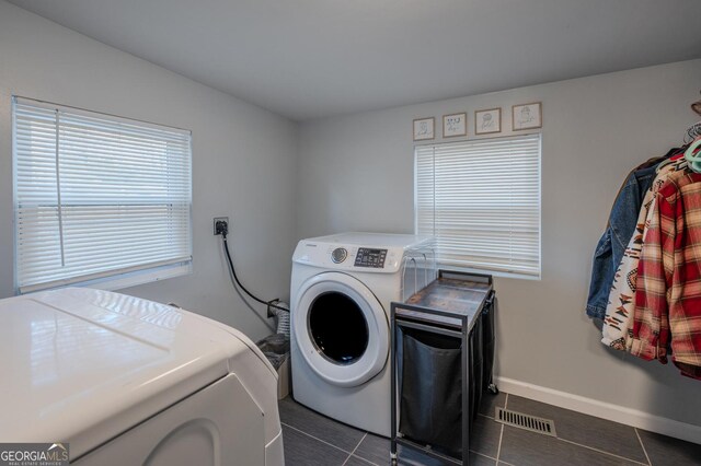 laundry area featuring washing machine and dryer and dark tile patterned floors