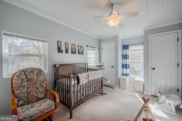 carpeted bedroom featuring ceiling fan, a crib, wood ceiling, and multiple windows