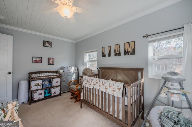 bedroom featuring a crib, light carpet, ceiling fan, and ornamental molding