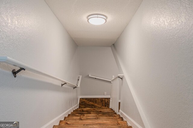 stairway featuring hardwood / wood-style floors and a textured ceiling