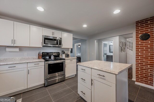 kitchen with light stone counters, white cabinets, stainless steel appliances, and a kitchen island