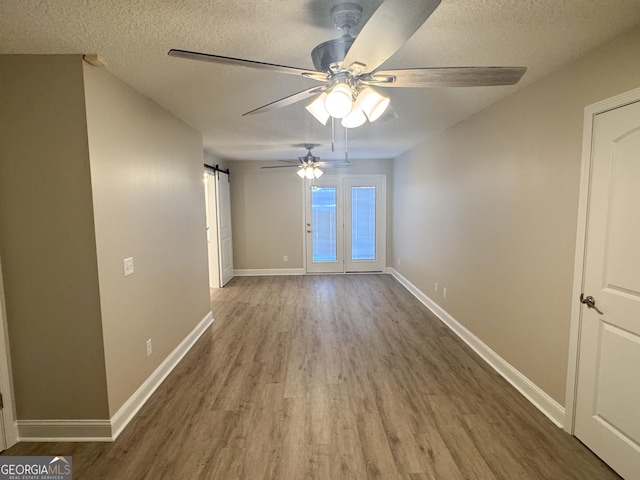 429 Deens Landing Rd, Baxley, GA 31513 - spare room with wood finished floors, a ceiling fan, a textured ceiling, baseboards, and a barn door