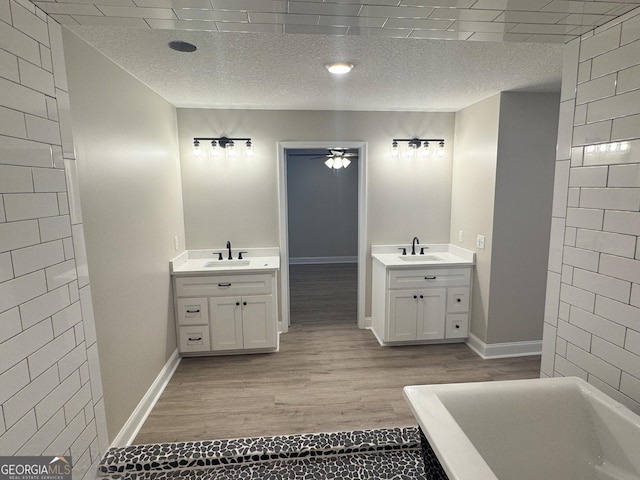 429 Deens Landing Rd, Baxley, GA 31513 - bathroom featuring two vanities, ceiling fan, wood finished floors, a textured ceiling, and a soaking tub