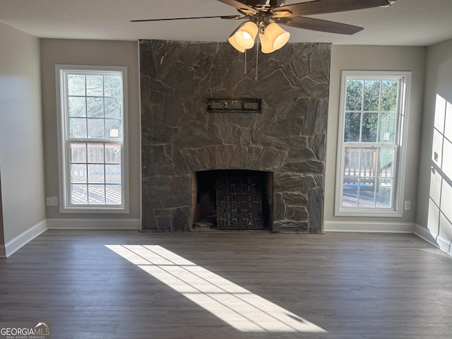 unfurnished living room featuring a fireplace, dark hardwood / wood-style flooring, and ceiling fan