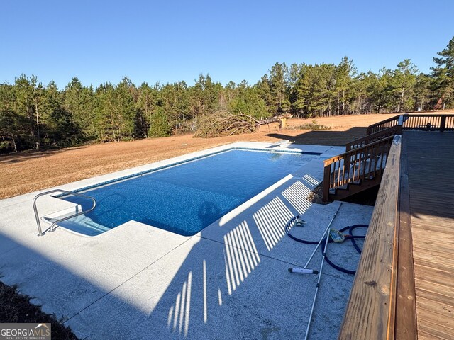 view of swimming pool featuring a wooden deck and a diving board