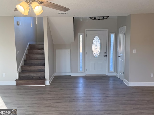 entrance foyer featuring a textured ceiling, ceiling fan, and dark wood-type flooring