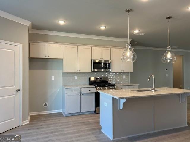 kitchen with white cabinets, appliances with stainless steel finishes, sink, and an island with sink